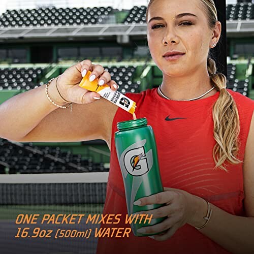 Athlete mixing hydration powder into a Gatorade bottle at a stadium.